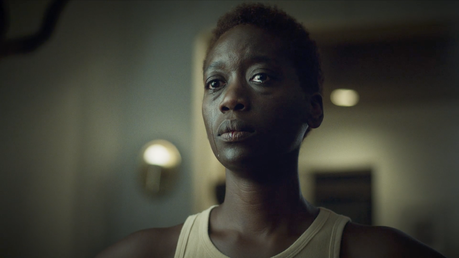 Close-up portrait of a woman with a single tear in somber light